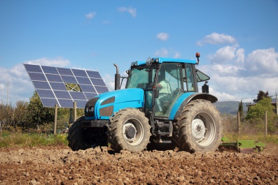 agriculture, tractor working on a field with photovoltaic solar panel in background